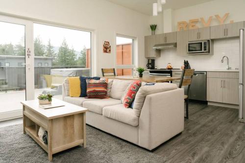 uma sala de estar com um sofá e uma cozinha em The Nest - Condo with Hot Tub & BBQ em Revelstoke