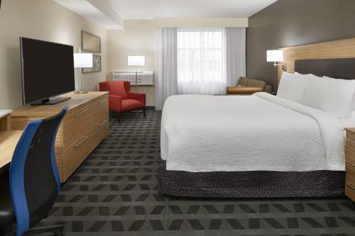 a hotel room with a bed and a flat screen tv at TownePlace Suites by Marriott Oshawa in Oshawa