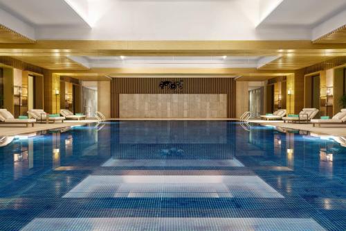 a swimming pool in a hotel lobby with chairs at Xiamen Marriott Hotel & Conference Centre in Xiamen
