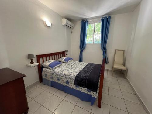 een slaapkamer met een bed met blauwe gordijnen en een raam bij Maison type F4 vue sur mer in Le Gosier