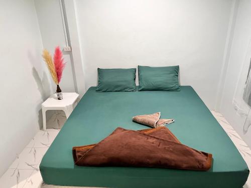 a bedroom with a bed with a green bedspread and acknowled at Phangan Dream box in Baan Tai