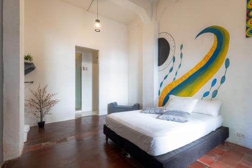 a bedroom with a bed with a painting on the wall at Media Luna Hostel Cartagena in Cartagena de Indias