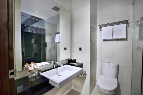 a bathroom with a white sink and a toilet at Neo Dipatiukur Bandung by ASTON in Bandung