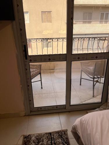 a room with a view of a balcony with two chairs at Badr pyramids view in Cairo