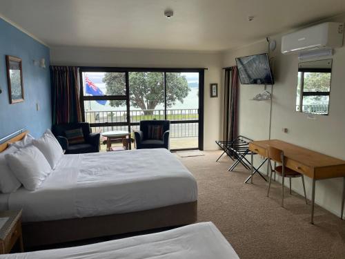 a hotel room with a large bed and a desk at Bay Sands Seafront Studios in Paihia