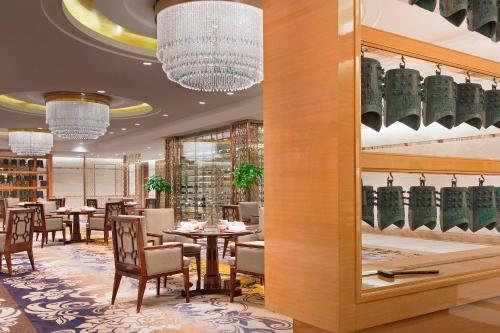 a dining room with tables and chairs and chandeliers at Sheraton Grand Wuhan Hankou Hotel in Wuhan