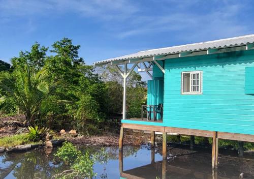 une maison bleue à côté d'une masse d'eau dans l'établissement Coco Key EcoLodge - Breakfast - Sea, à Bocas del Toro