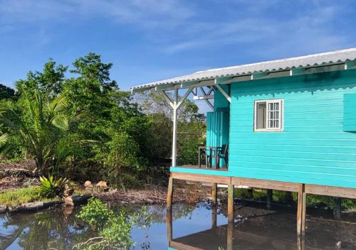 a blue house next to a body of water at Coco Key EcoLodge - Breakfast - Sea in Bocas Town