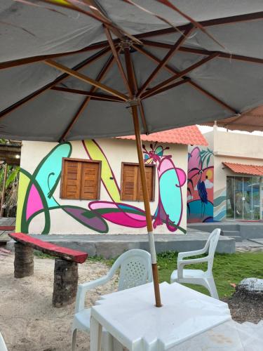 a table with an umbrella in front of a wall with graffiti at Camping Gnomo Místico in Olivença