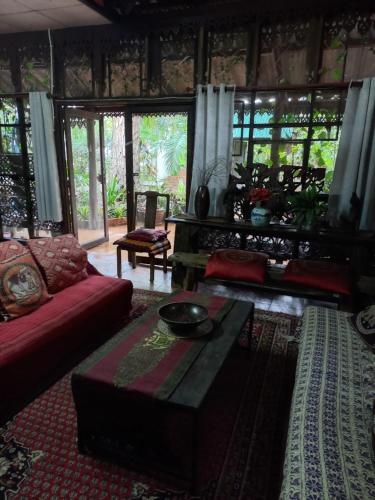 a living room with a red couch and a table at Teak house Chiang Mai in Chiang Mai
