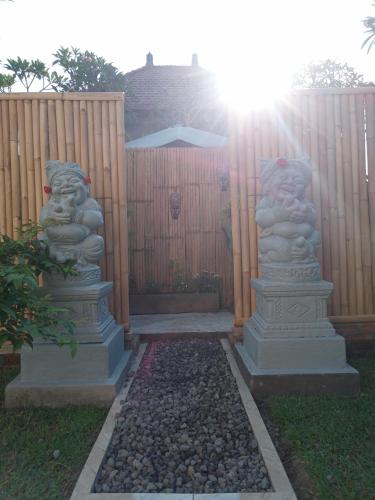 un jardín con dos estatuas frente a una valla en Chida Homestay, en Ubud