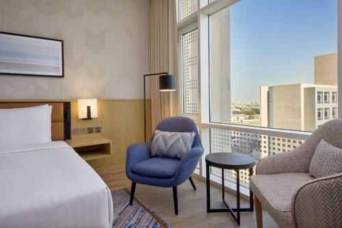 a hotel room with a bed and a chair and a window at Courtyard by Marriott Jubail in Al Jubail