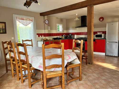 une cuisine avec une table, des chaises et des armoires rouges dans l'établissement Grande maison de charme avec jardin clos, idéale pour familles et amis, au cœur du Perche - FR-1-581-94, à Montireau