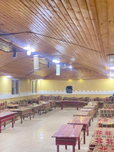 Sunrise Wadi Rum Camp في وادي رم: غرفة كبيرة مع طاولات وكراسي خشبية