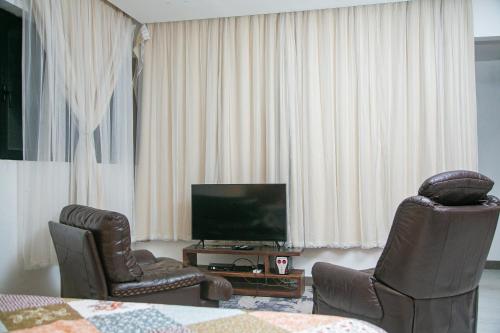 sala de estar con 2 sillas y TV en Toilcam en Buea