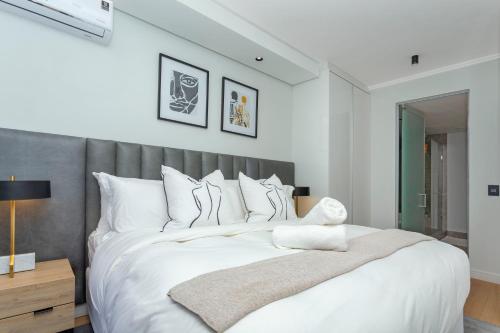 a bedroom with a large white bed with a gray headboard at Luxury Haven at Ellipse Waterfall in Midrand