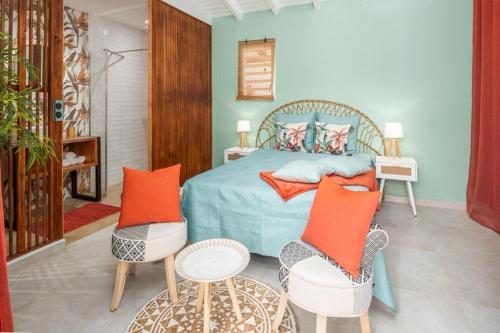 a bedroom with a bed with orange pillows and chairs at Villa Papillon in Baie-Mahault