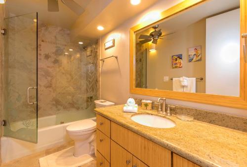 ein Badezimmer mit einem Waschbecken, einem WC und einem Spiegel in der Unterkunft Maui Parkshore 312 - MCH in Kihei