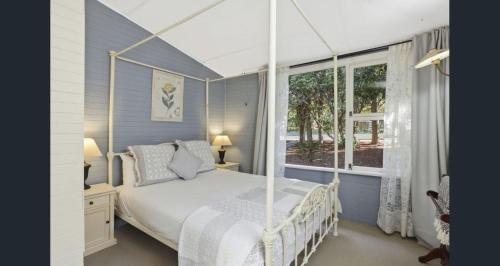 um quarto com uma cama de dossel e uma janela em Arohanui em Katoomba
