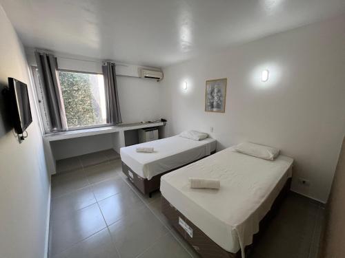 Habitación pequeña con 2 camas y ventana en Manacá Hotel, en Foz do Iguaçu