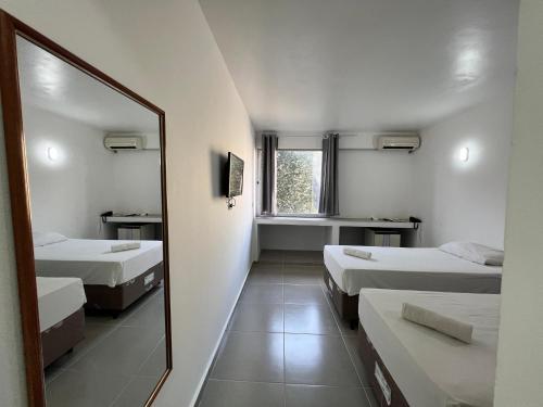 um quarto com duas camas e um espelho em Manacá Hotel em Foz do Iguaçu