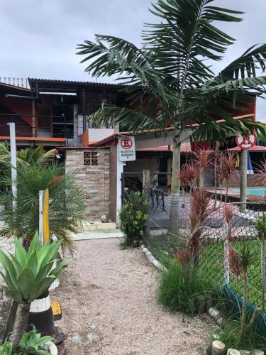 a building with a palm tree in front of it at Casa de temporada Xerém in Duque de Caxias