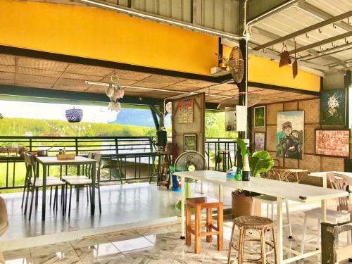un restaurant avec des tables et des chaises et une grande fenêtre dans l'établissement Chompunud House589 ชมพูนุชเฮ้าส์589, à Ban Don Klang