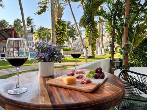 アカプルコにあるDepto acogedor en Acapulco Diamante - Sin daños por OTISのワイン2杯とフルーツプレート付きテーブル