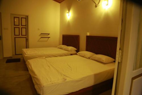two beds in a small room with a door at Serenity Villa Anuradhapura in Anuradhapura