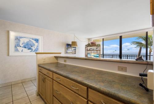 a kitchen with a bar with a view of the ocean at Sugar Beach 522 - MCH in Kihei