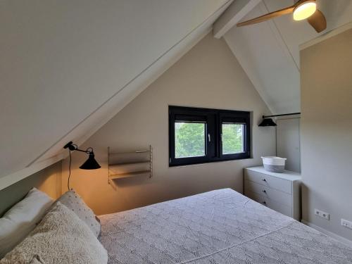 1 dormitorio en el ático con cama y ventana en Luxurious detached water villa with jetty, en Balk