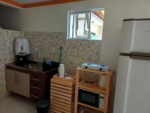 a small kitchen with a sink and a refrigerator at Aconchego da Kika in Caruaru