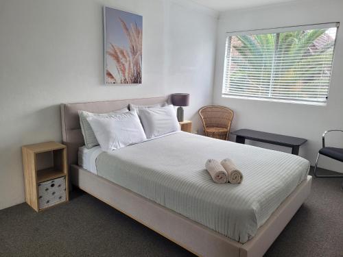 a bedroom with a bed with two slippers on it at Reef Resort Apartments in Mona Vale