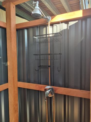 a shower in a room with a metal wall at Birdsong Retreat - A BnB on Lamb Island 