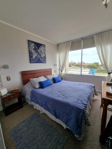 1 dormitorio con cama con sábanas azules y ventana en Arriendo vacaciones reñaca, en Viña del Mar