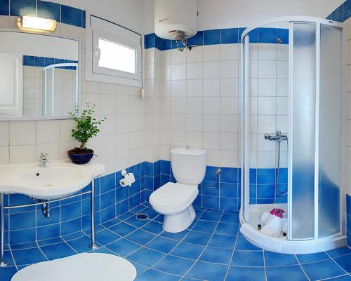 Baño de azulejos azules con aseo y lavamanos en Glyfa Corfu Apartments, en Barbati