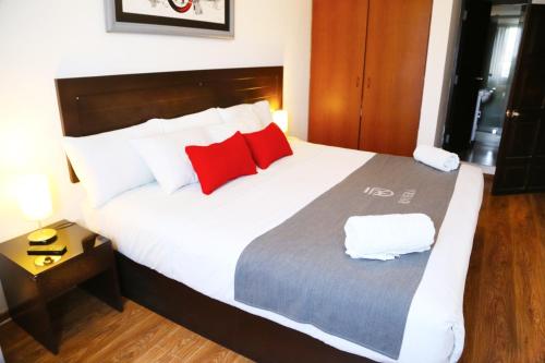 ein Schlafzimmer mit einem großen weißen Bett mit roten Kissen in der Unterkunft Hoteles Riviera Ejecutivo in Arequipa