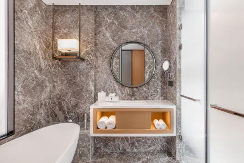 a bathroom with a tub and a sink and a mirror at The Westin Wuhan Hanyang in Wuhan