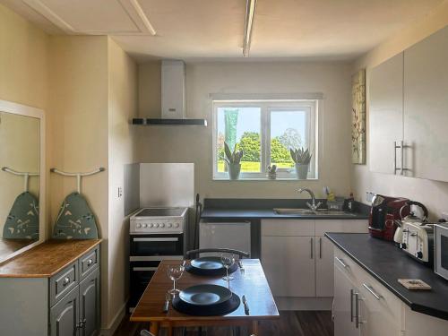 a kitchen with white cabinets and a table with plates on it at The Lodge in Pauntley