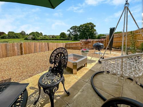 a patio with a swing and a fire pit at The Lodge in Pauntley