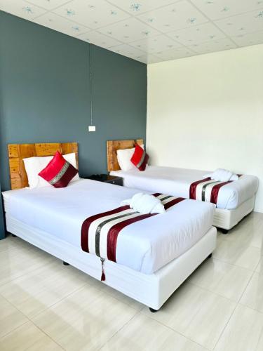 two beds in a hotel room with white and red pillows at Diamond de pai in Pai