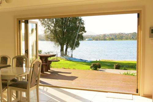 a sliding glass door to a patio with a view of the water at Waterfront Lakeside Cottage Primbee in Primbee