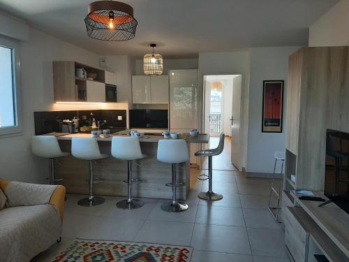 une cuisine avec un bar et des tabourets. dans l'établissement Charmant appartement neuf à Capbreton avec balcon, Wifi, et parking sécurisé pour 5 personnes - FR-1-239-1004, à Capbreton