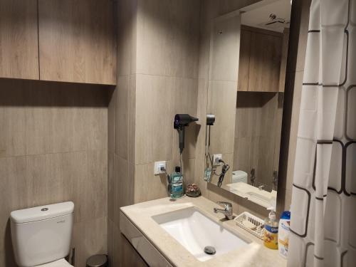 een badkamer met een wastafel, een toilet en een spiegel bij Irvine Suites Lantai 26-I2618 in Cikarang