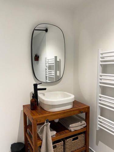 a bathroom with a sink and a mirror on a table at Tiny house 15min away from Opera Garnier in Argenteuil