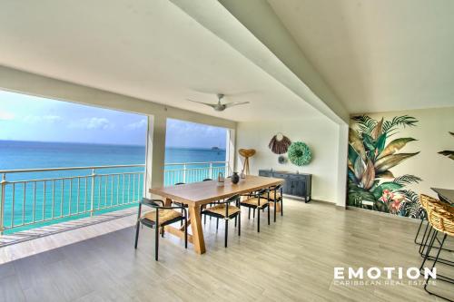 a dining room with a table and chairs and the ocean at Appartement 2 chambres sur la belle plage de grand case in Grand Case