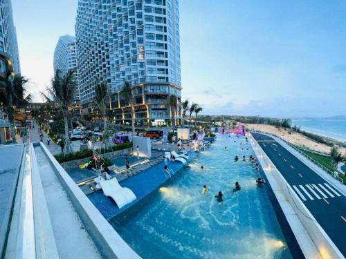 a large swimming pool next to a beach with people in it at Apec Mandala Mũi Né Condotel in Mui Ne