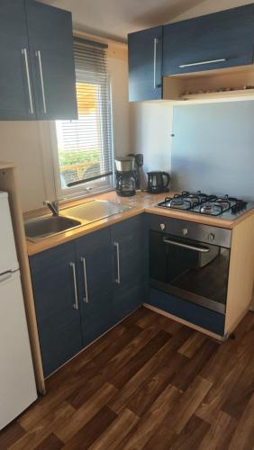 a kitchen with blue cabinets and a stove top oven at Mobilhome 6 couchages in Vic-la-Gardiole