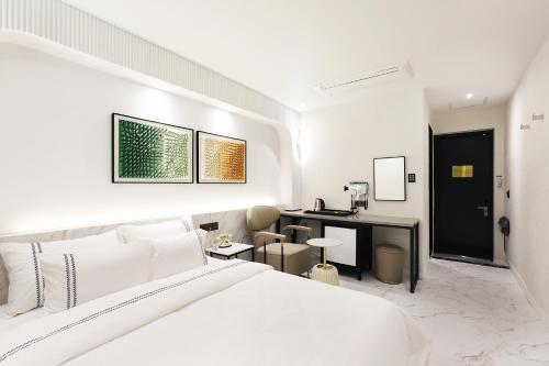 a white bedroom with a bed and a desk at Mari Hotel in Chungju