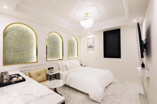 a white bedroom with a large bed and a couch at Mari Hotel in Chungju